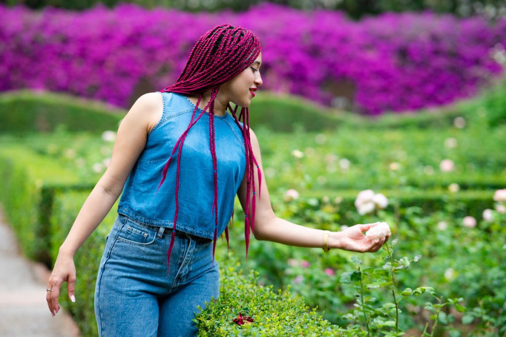 chica con pelo rosa toca flor en jardín de Monforte. Carlos Gimart