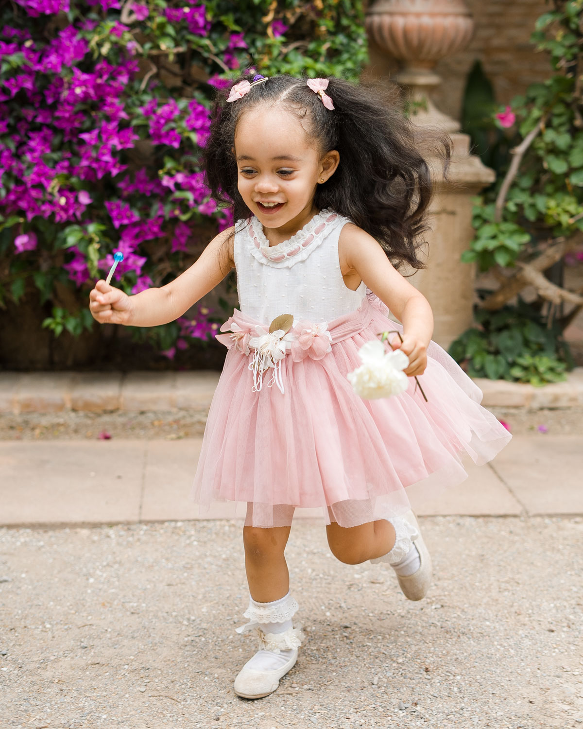 niña corre en sesión de Comunión en jardín de Monforte