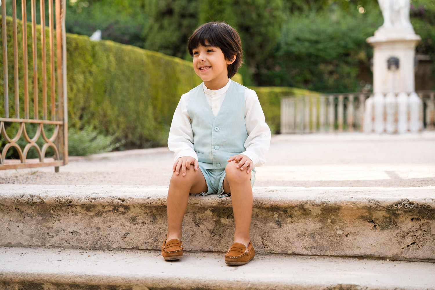retrato de niño sentado en escalón en jardín