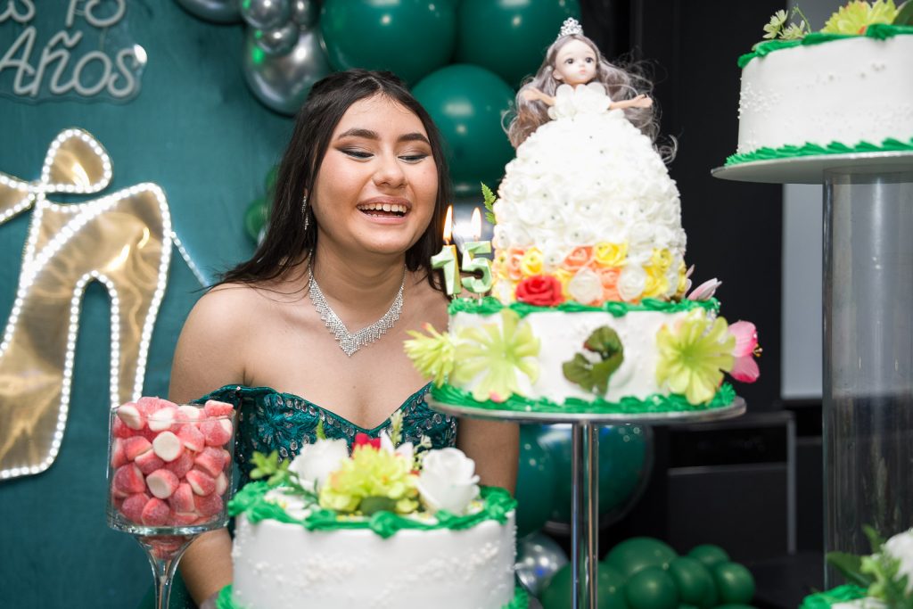 niña sonríe delante de su tarta de cumpleaños de 15 años