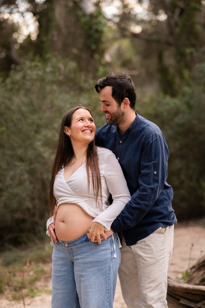 Pareja sonriente en sesión de embarazo.