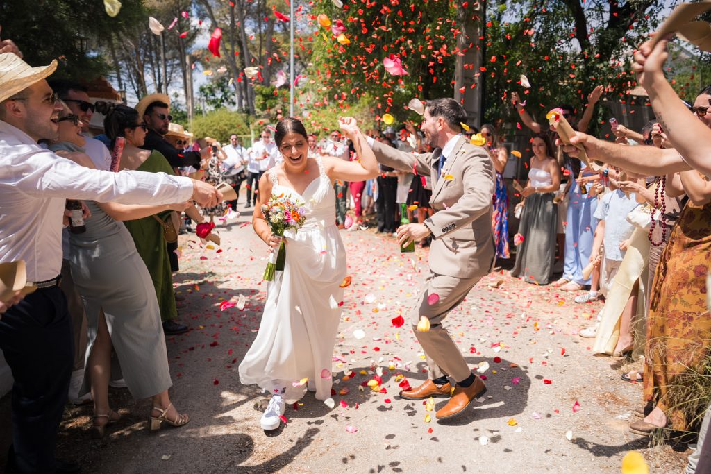 novios corren e invitados les lanzan pétales de flores