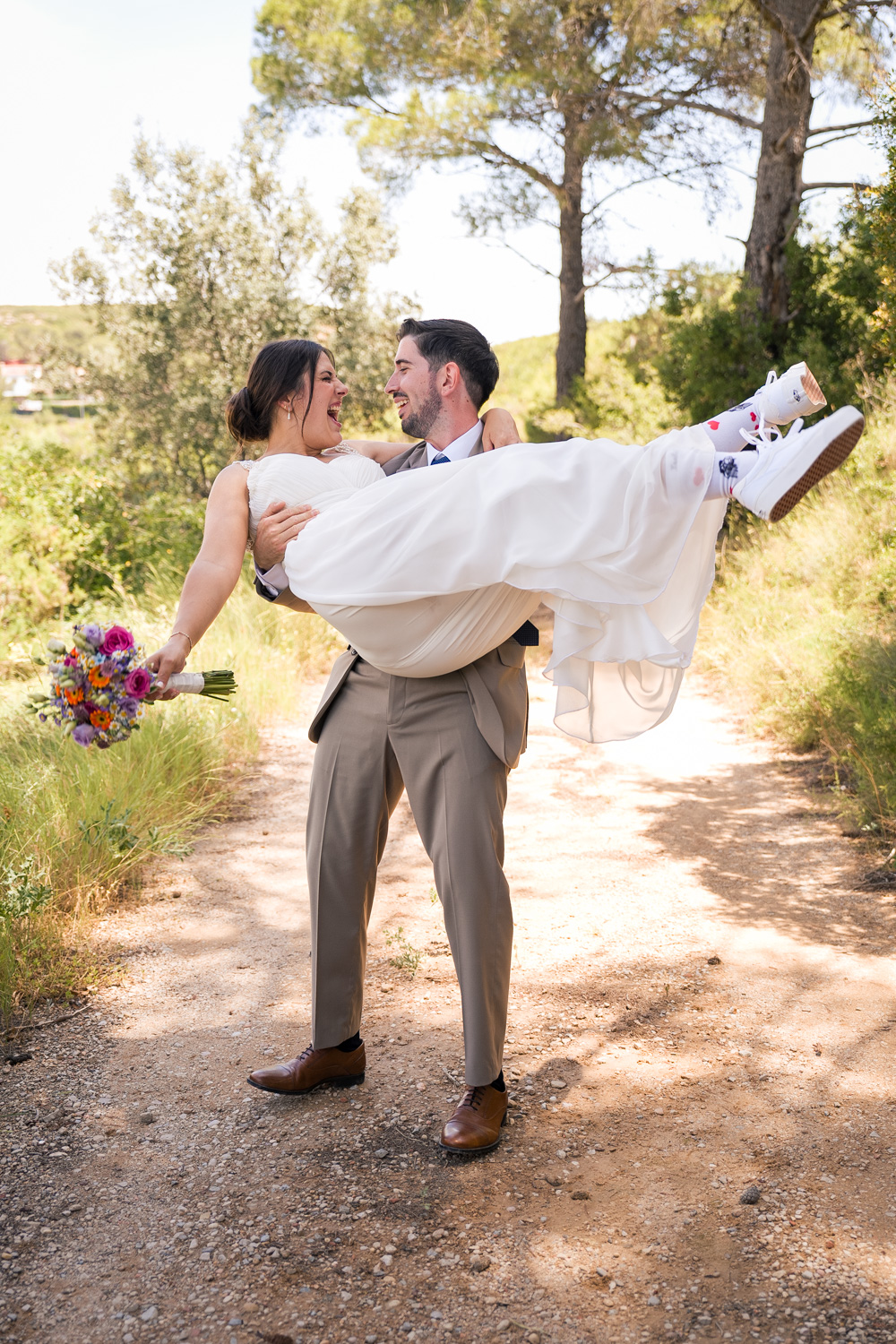 novio levanta a novia en brazos en camino de monte