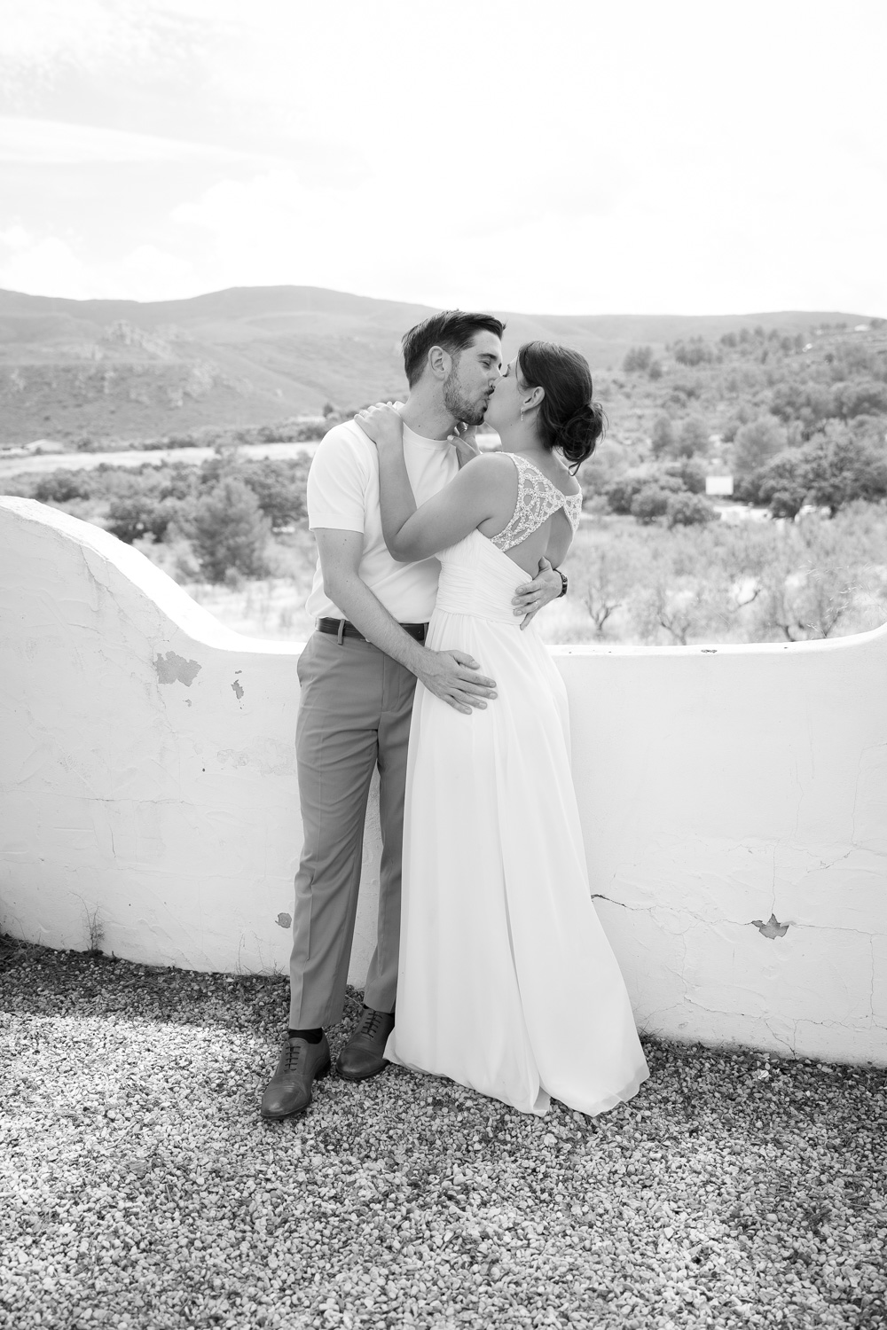 Beso de novios de boda en blanco y negro entre las montañas